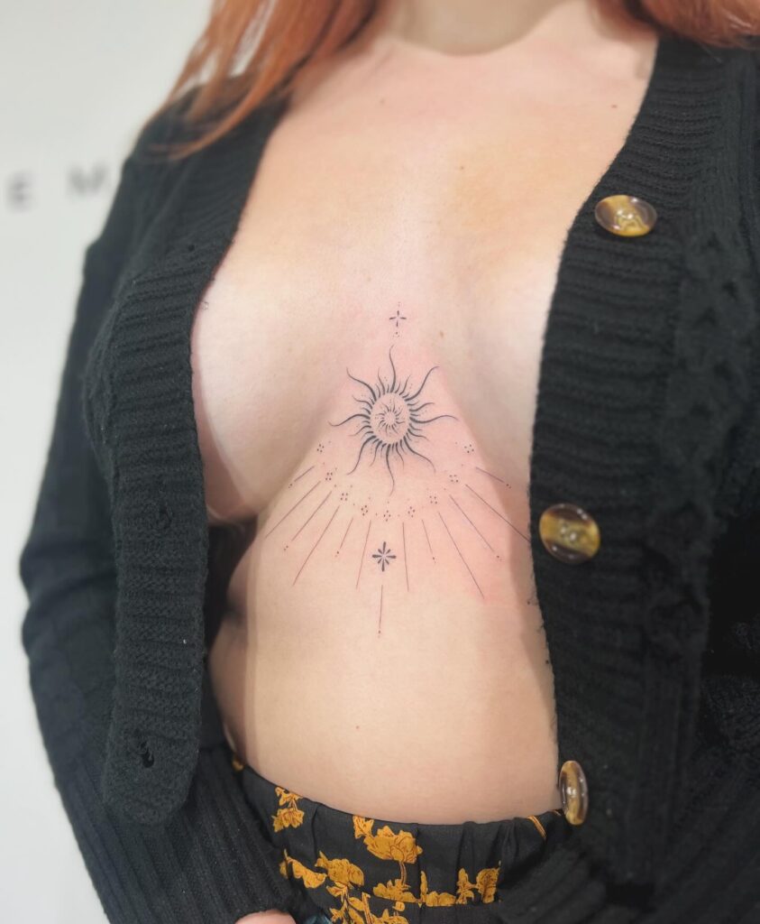 Celestial sun sternum tattoo with intricate radiating line details