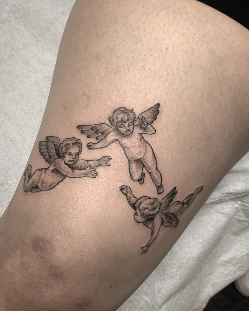 Cherubs in flight a dreamy above the knee tattoo for females