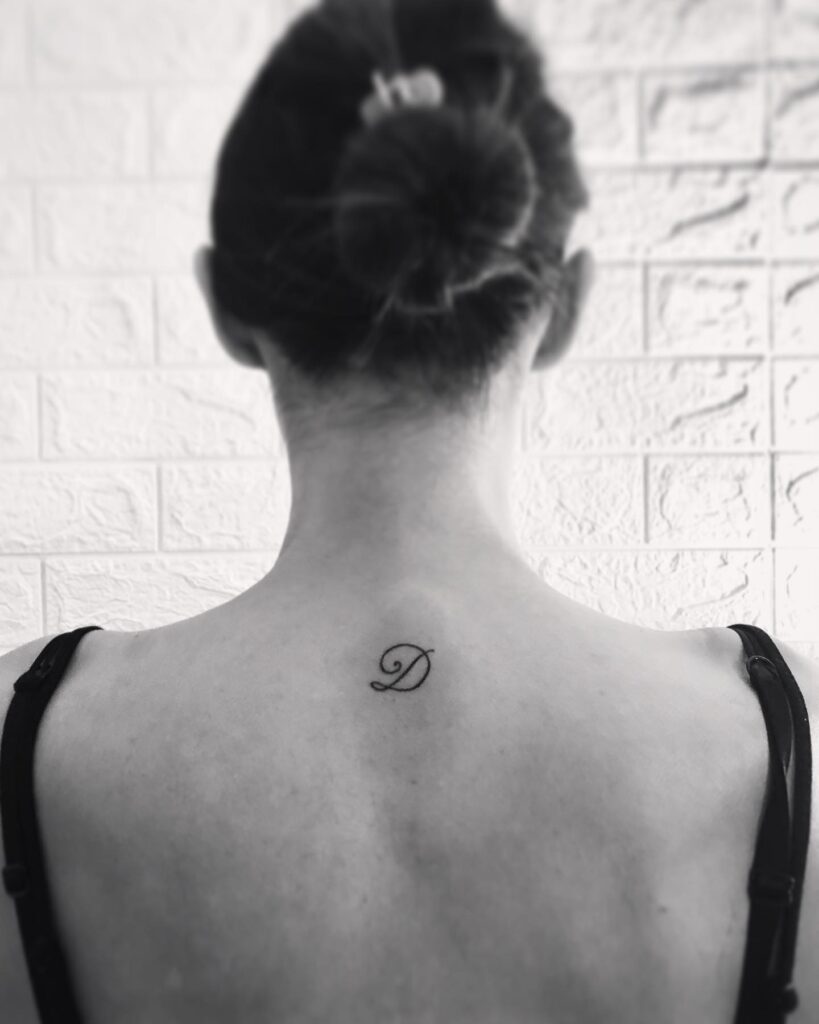 Classic 'D' Letter Tattoo Adorning the Back of the Neck: Neckline Chic