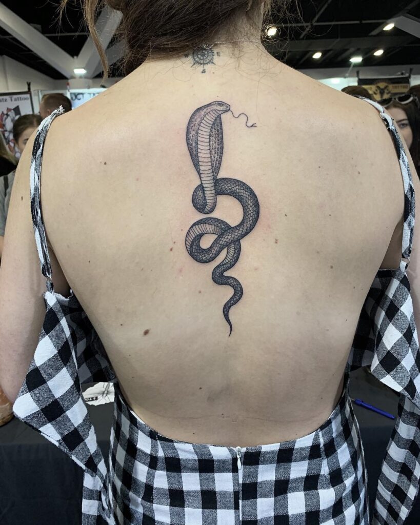 Classy side view cobra tattoo on the back, tongue out for added attitude: elegant menace