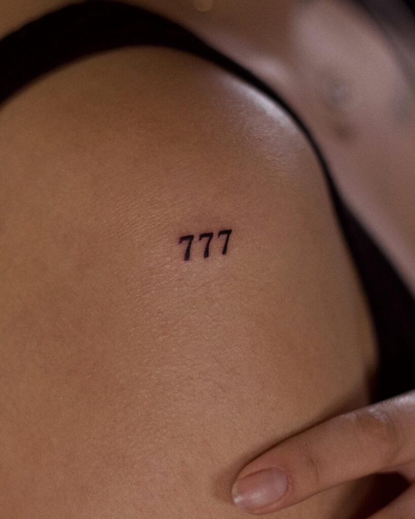Clean 777 number tattoo on the shoulder, a small and elegant upper tattoo shoulder charm 