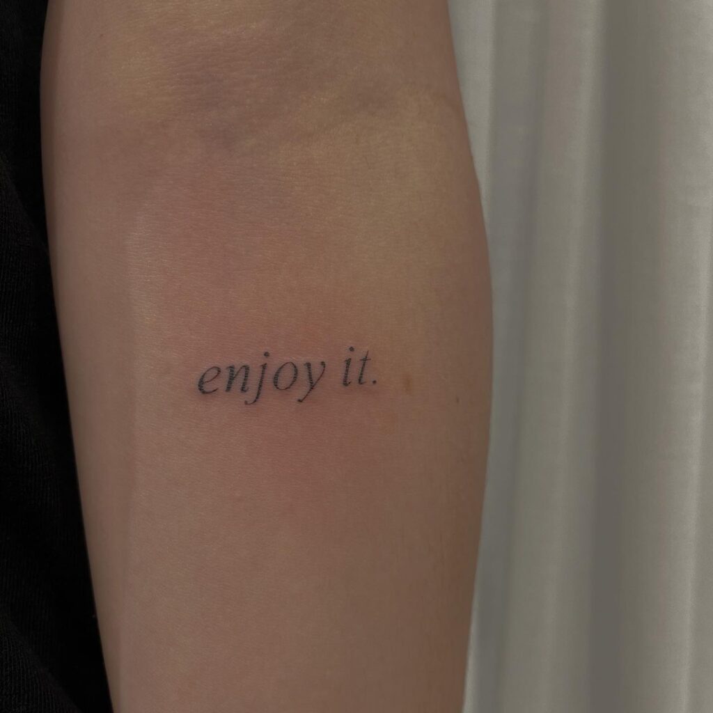 Clean and simple words lettering tattoo on the forearm, reminding to 'enjoy it.': enjoy every moment
