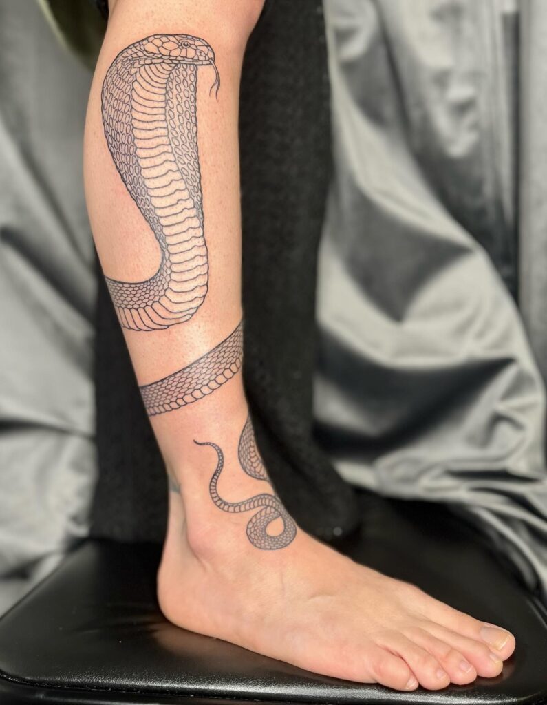 Cobra snake wrapped around leg tattoo for a striking feminine look: serpentine elegance