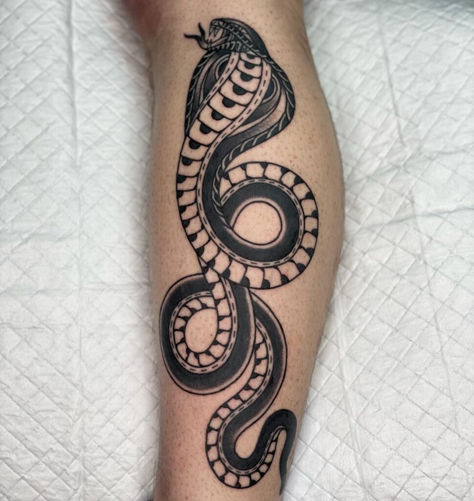 Cobra tattoo on the side of the calf in black work: high contrast elegance