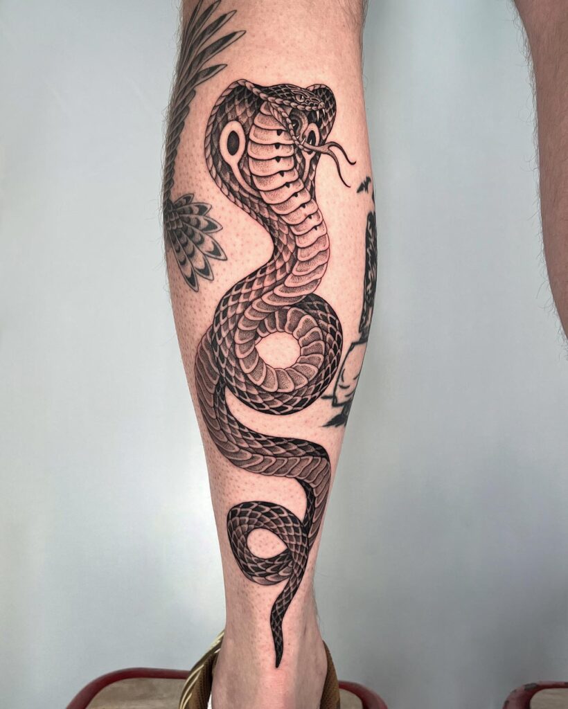 Cobra tattoo with patterns, head up and tongue out on the calf: traditional striking