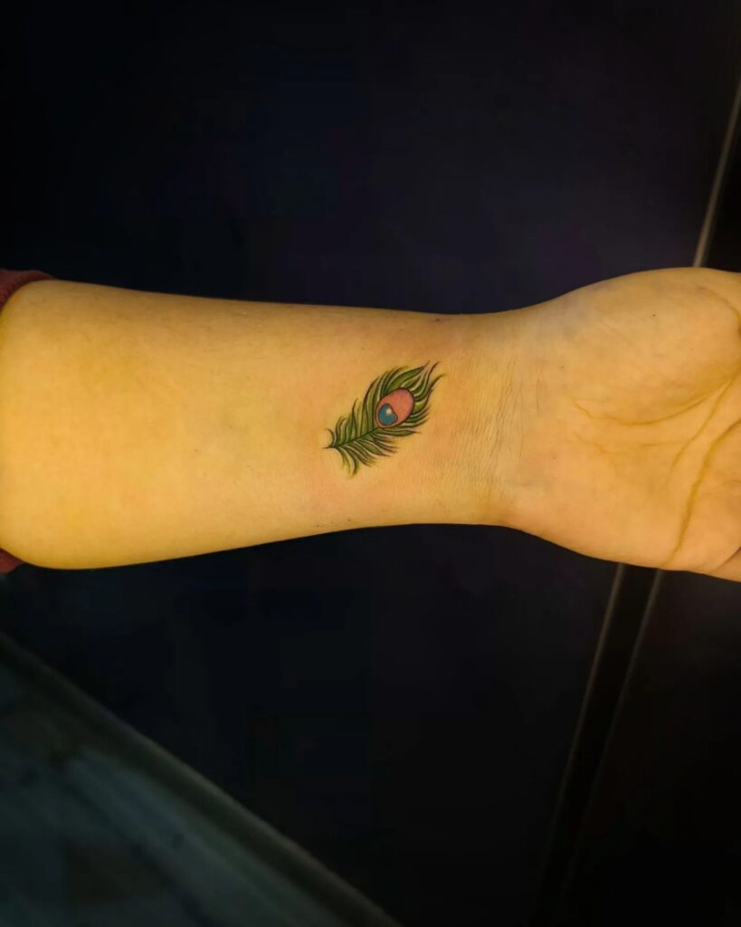 Colorful Peacock Feather Tattoo on Forearm Vibrant Symbolism