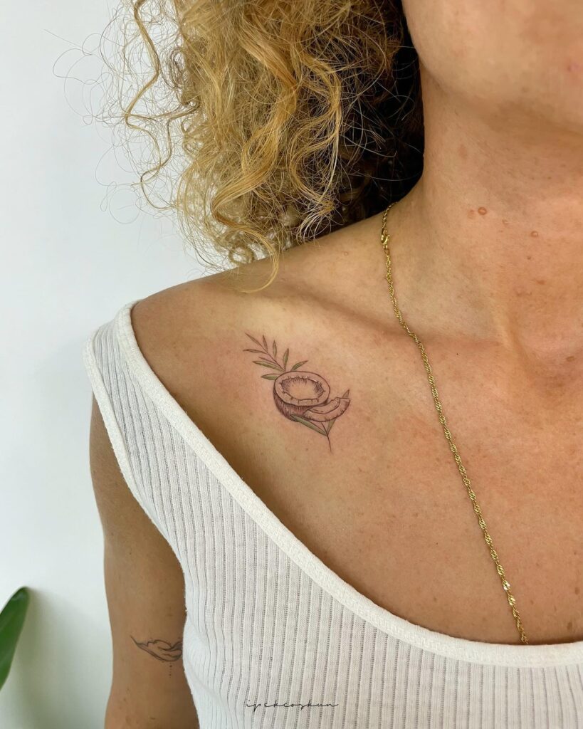 Colorful coconut tattoo with green leaf on the collarbone, an opened coconut art: tropical essence