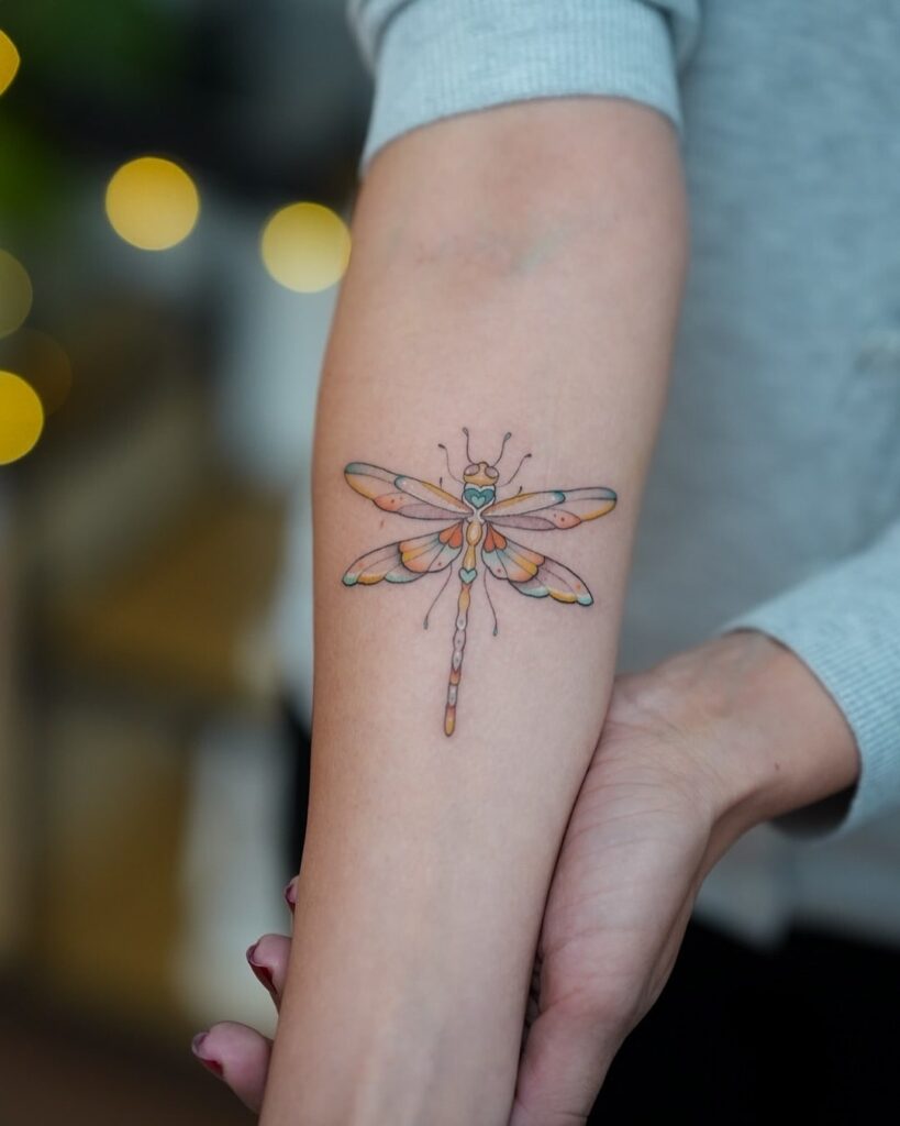 Colorful Dragonfly Forearm Tattoo with Pastel Shades and Playful Design