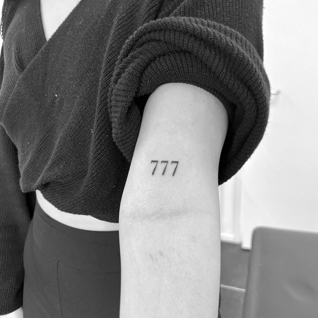 Cute 777 number tattoo above the elbow, tailored for a delicate and feminine look elbow elegance 