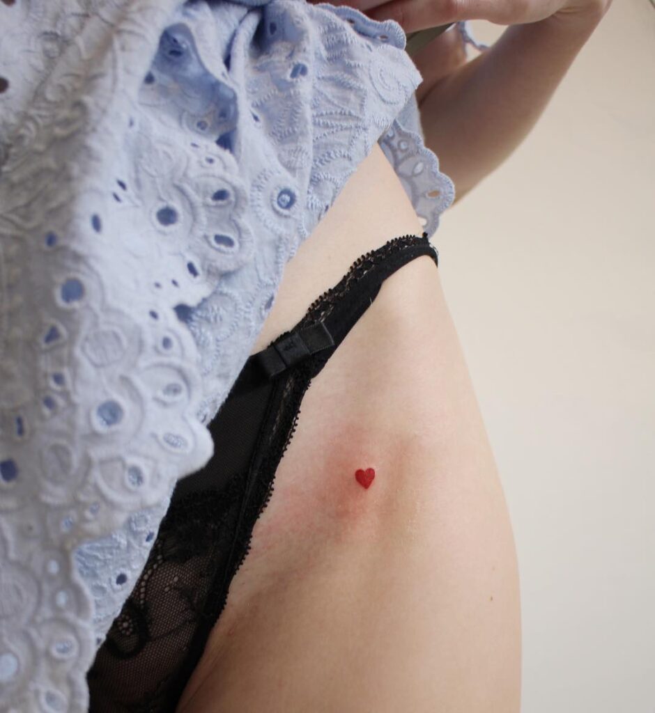 Cute and red little filled hip tattoo for women
