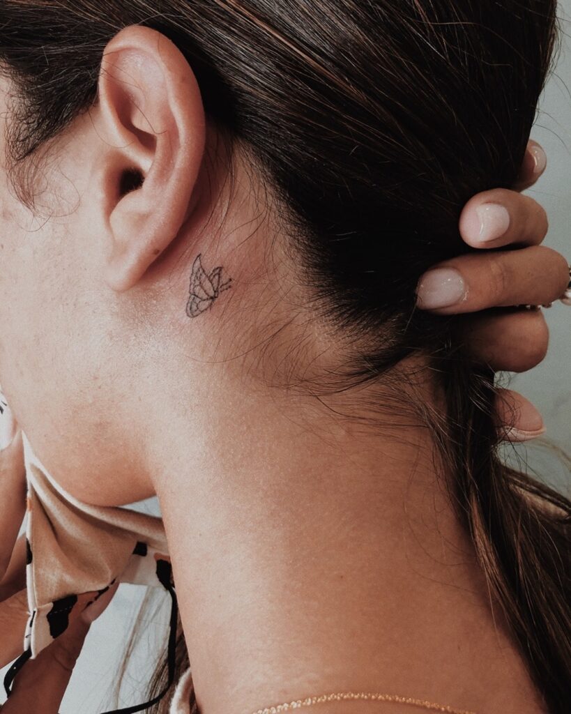 Cute and tiny butterfly tattoo below the ear for a touch of feminine delicacy