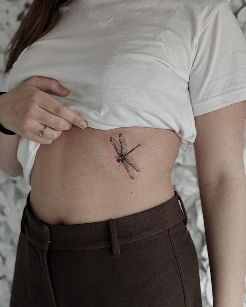 Cute realistic dragonfly tattoo on the rib: delicate flying insect ink