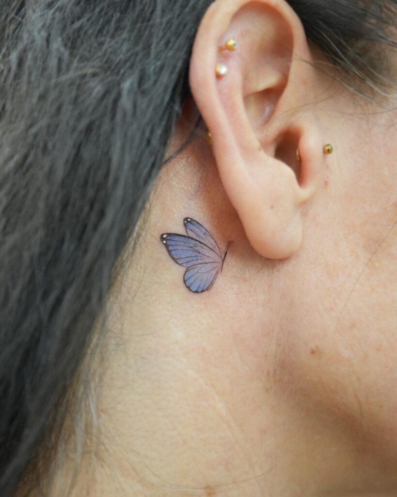 Dark blue moving butterfly tattoo behind the ear mysterious allure