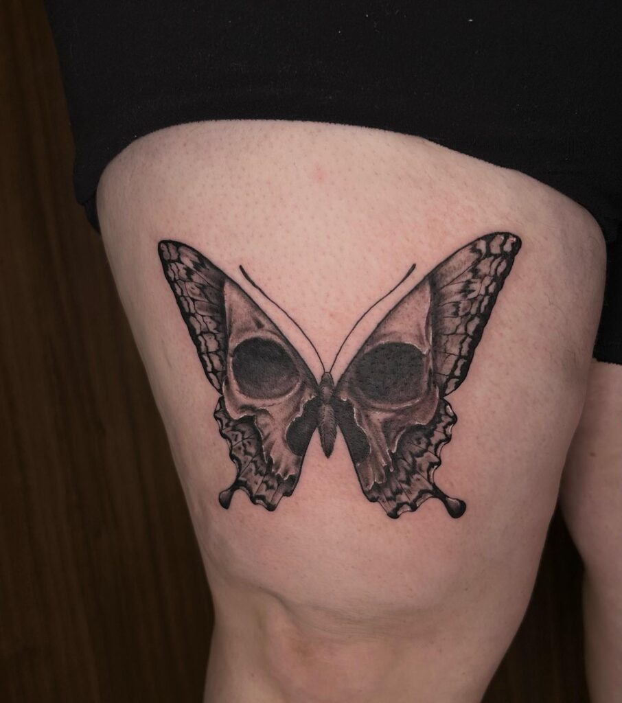 Dark traditional skull butterfly tattoo a gothic fusion on thigh