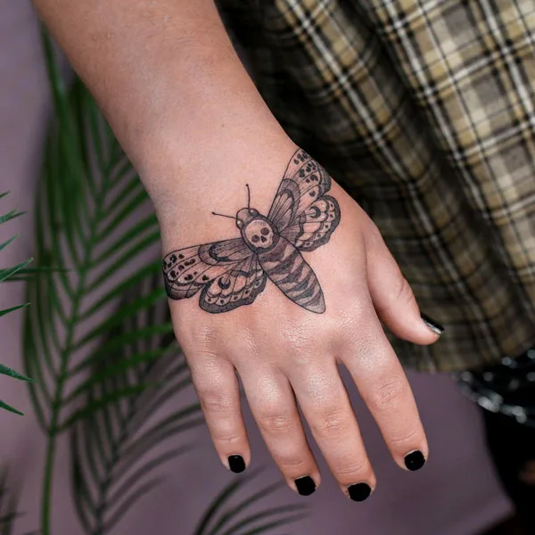 Death moth hand tattoo