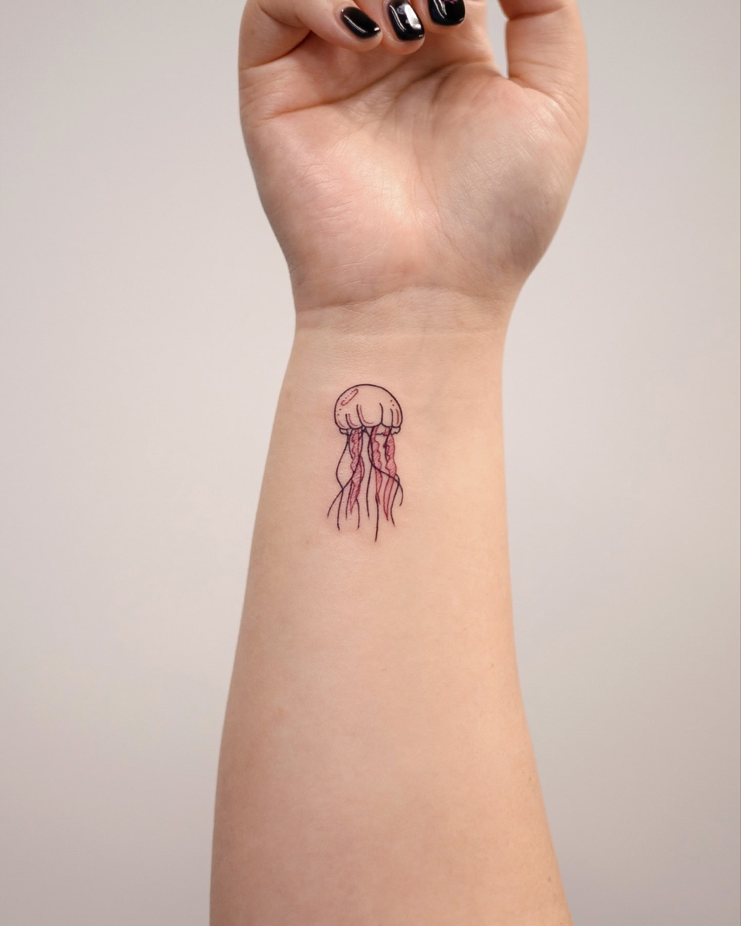 Delicate jellyfish tattoo on wrist symbolizing resilience flow