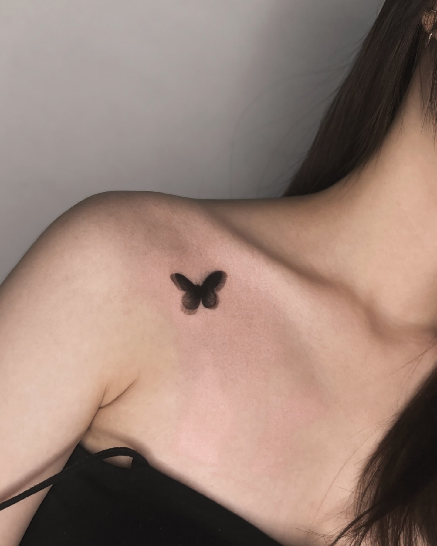 Delicate shadow butterfly tattoo under collarbone meaning