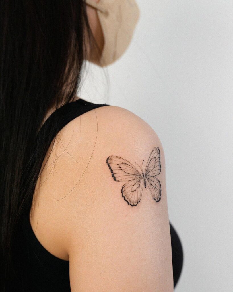 Delicate silhouettes outline butterfly tattoo on shoulder and arm