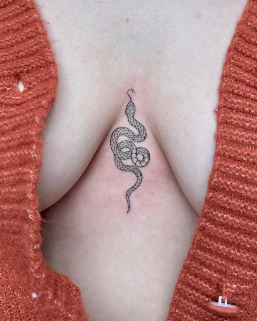 Delicate snake sternum tattoo symbolizing transformation and rebirth