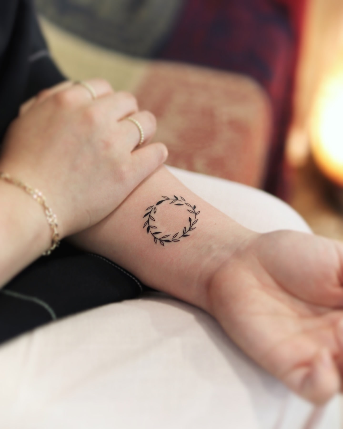 Delicate wreath tattoo on wrist symbolizing growth and eternity