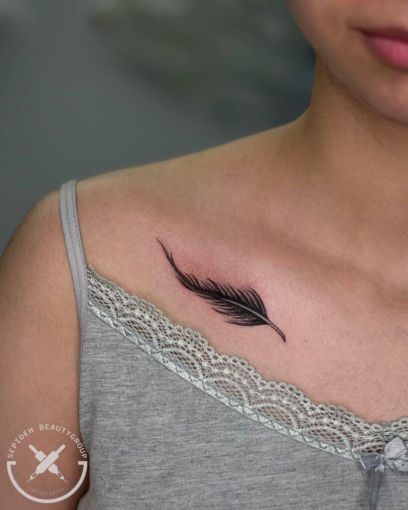 Detailed and creative black shaded feather tattoo on the collarbone feathers of creativity