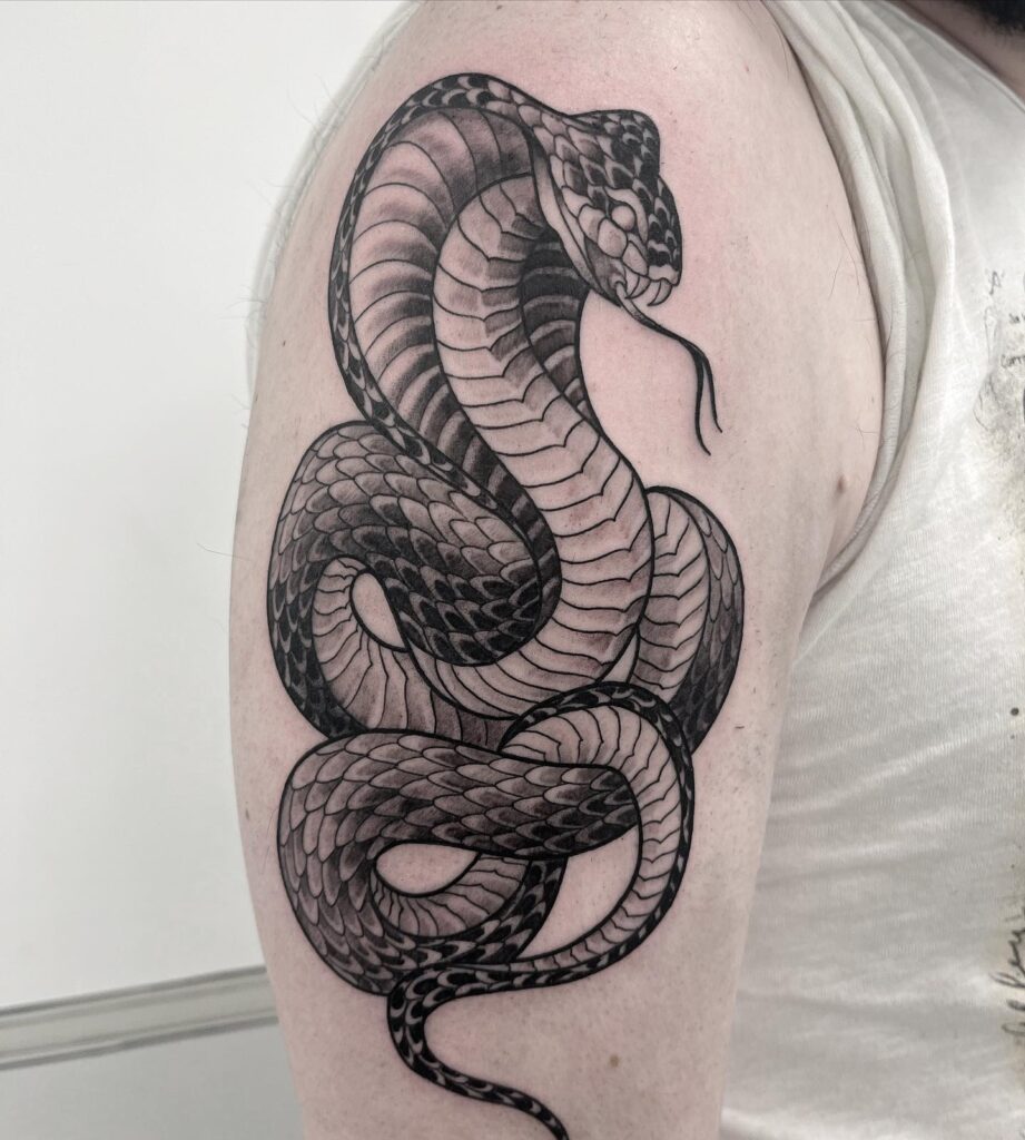 Detailed cobra with tongue out tattoo on the upper arm: royal charm