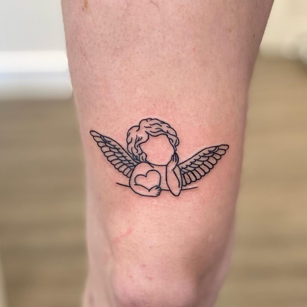 Discovering cherubic charm a cute little cherub tattoo above the knee