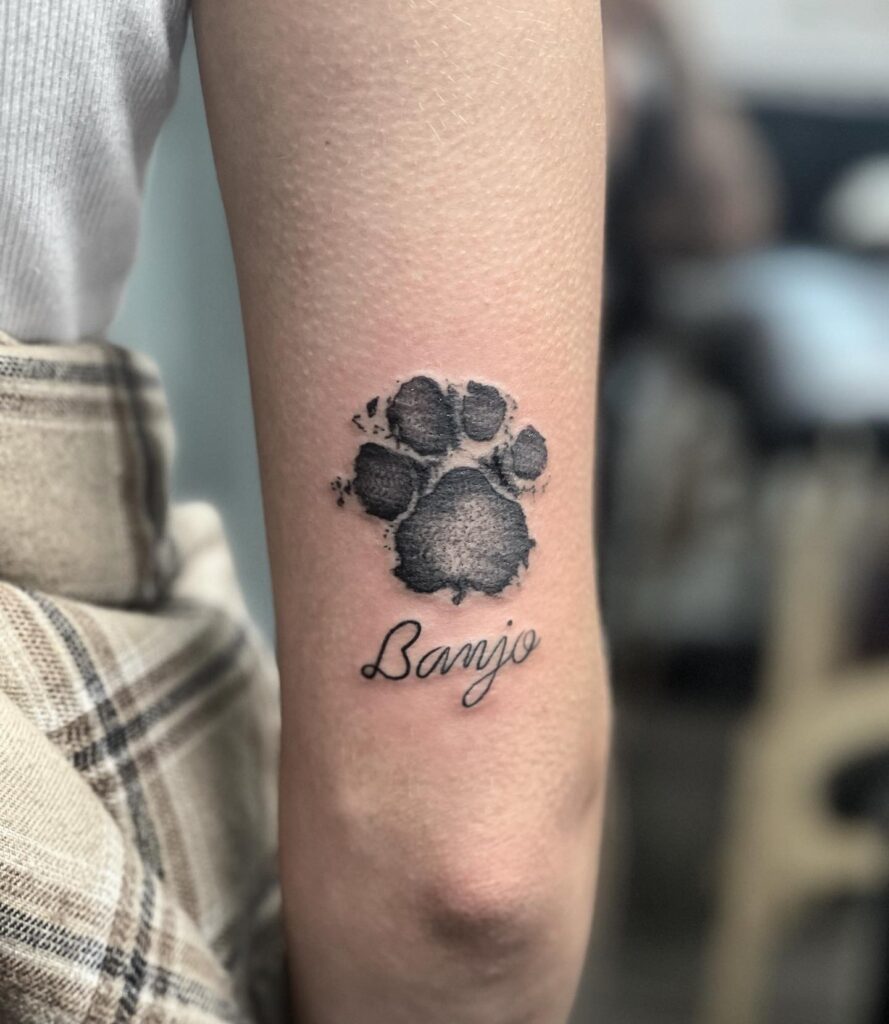 Dog Paw Print Tattoo on the Back of the Elbow with 'Banjo' Script: Memorial Majesty