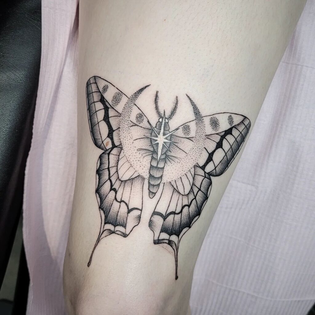 Dotwork delight intricate moth tattoo above the knee