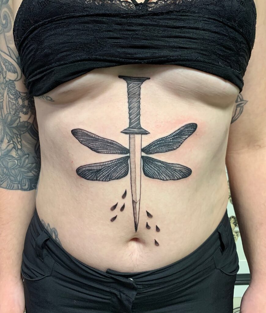 Dragonfly Wings Tattoo Amidst a Big Sword Tattoo on the Stomach: Mystical Fusion