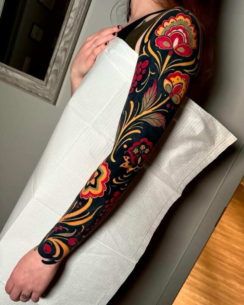 Eastern European-inspired floral tattoo sleeve with rich red and gold hues for women