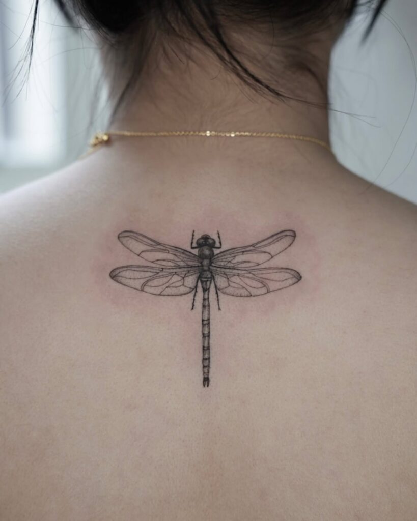 Elegant Fine-Line Dragonfly Tattoo on Upper Back Symbolizing Transformation