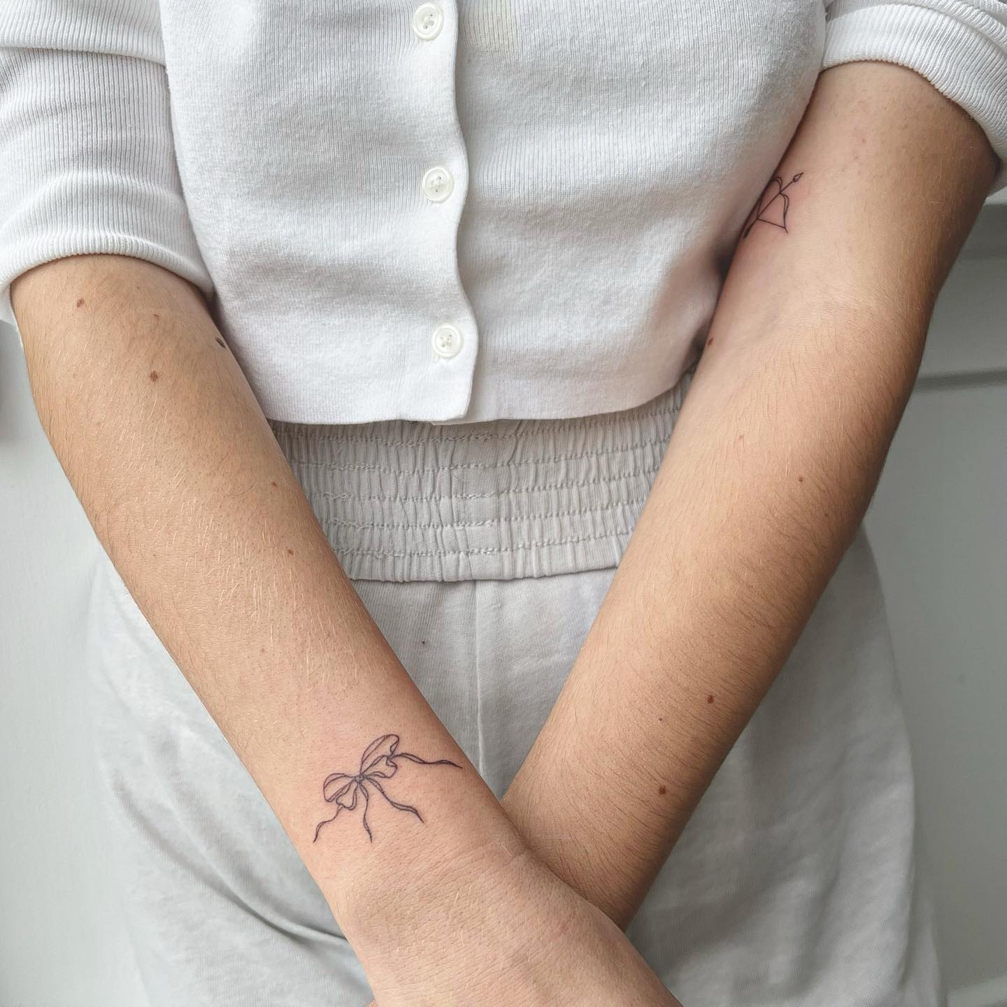 Elegant Flowing Ribbon Bow Tattoo on Wrist Symbolizing Femininity and Memories