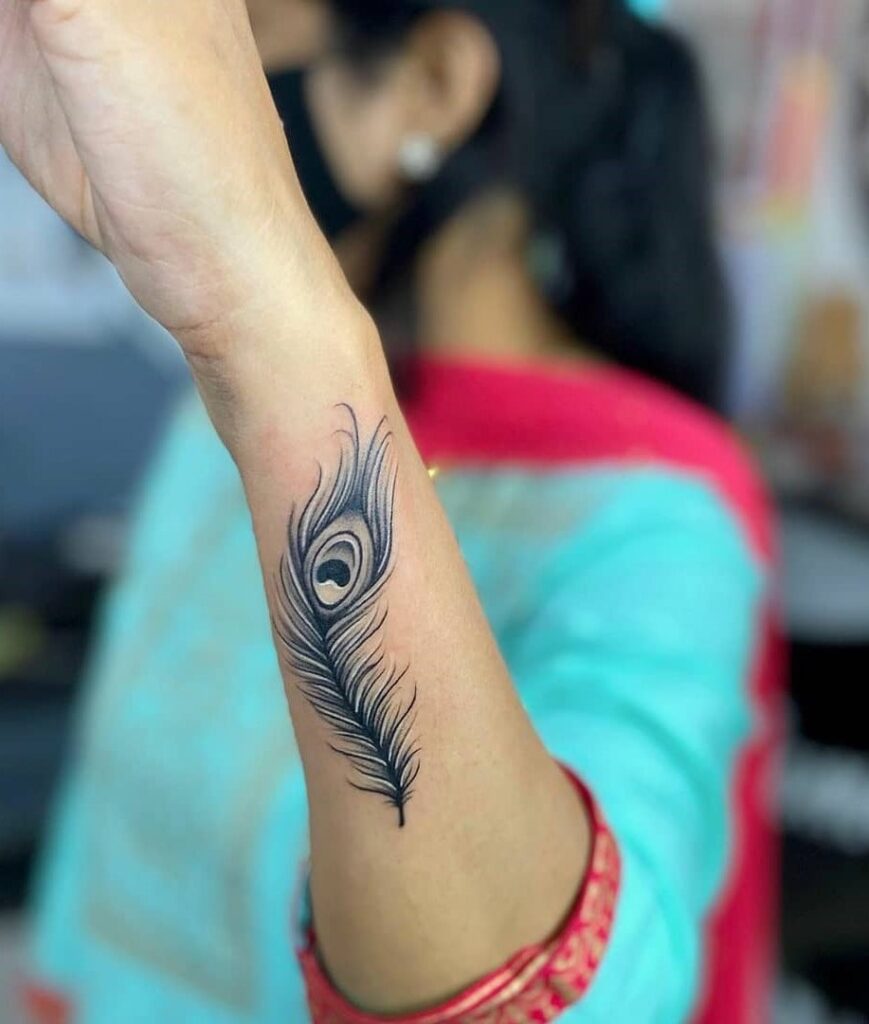 Elegant outer forearm peacock feather tattoo in black a unique choice for women