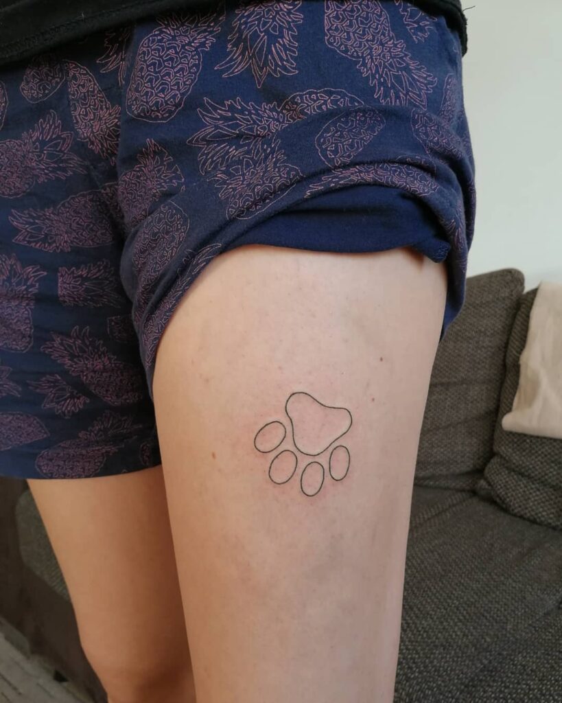 Elegant Outline Paw Print Tattoo on the Thigh: Handpoke Harmony