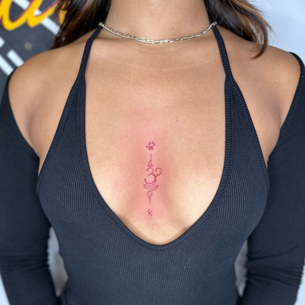 Elegant red ink script sternum tattoo with spiritual and personal meaning