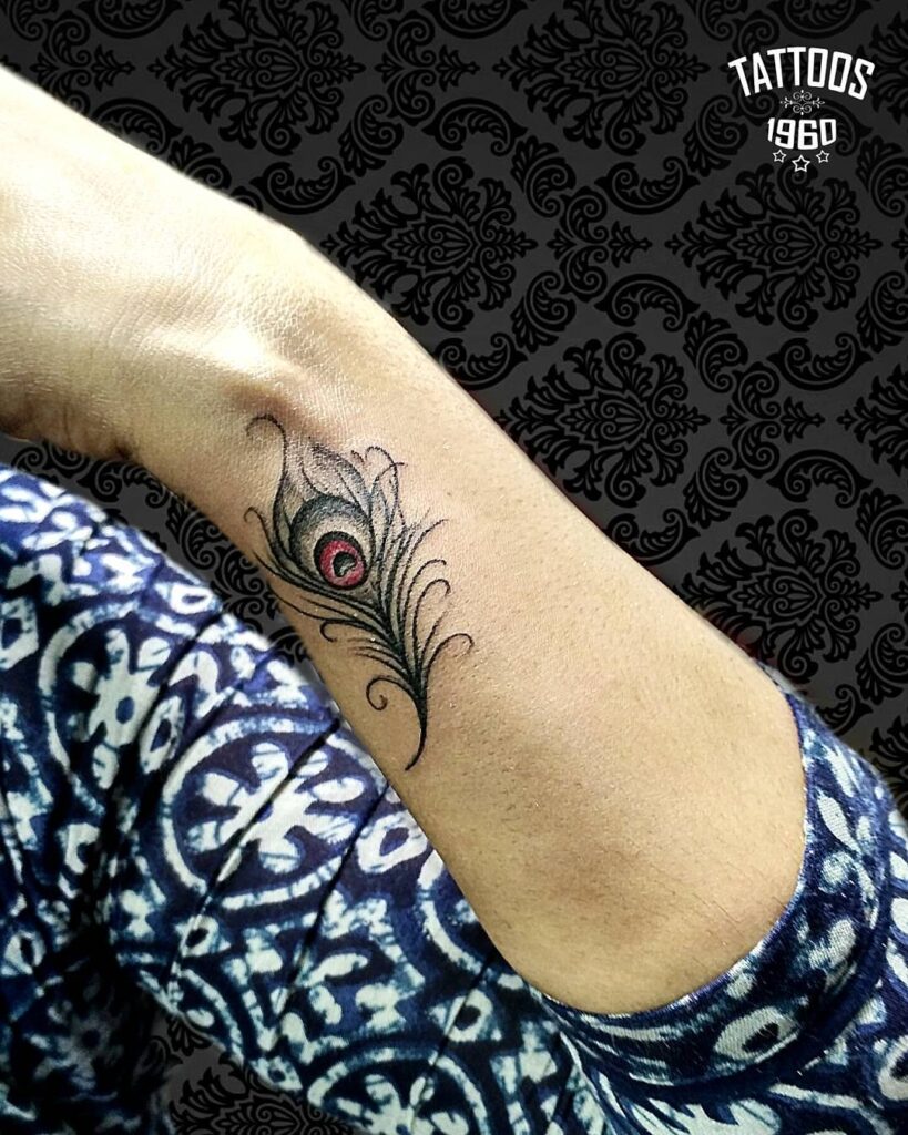 Expressive red and black wrist peacock feather tattoo a captivating design