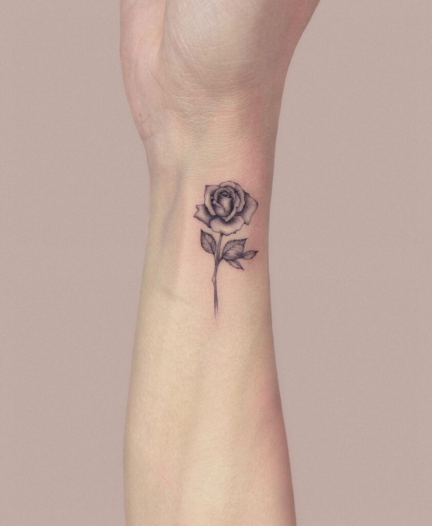 Exquisite and elegant a tiny rose plant tattoo on the side wrist