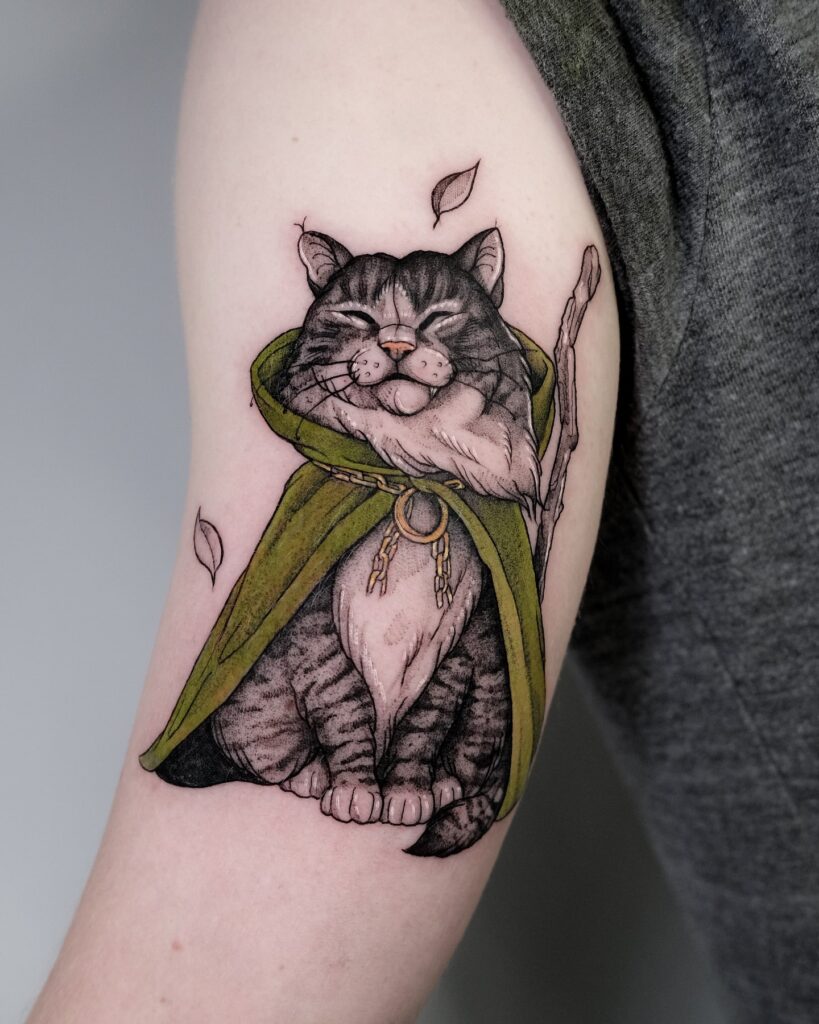 Fantasy cat wizard tattoo with cloak and staff on forearm