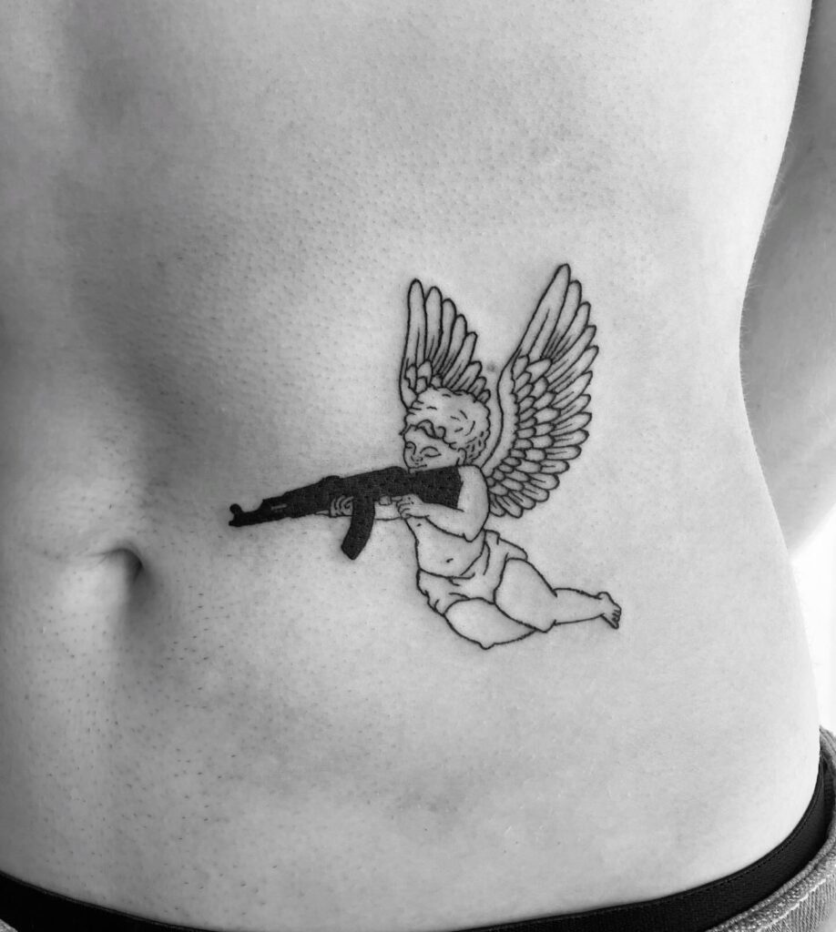 Female Angel with Gun and Wings Tattoo on the Side Stomach: Fierce Elegance