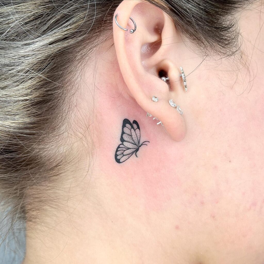 Female moving butterfly tattoo behind the ear a dance of grace