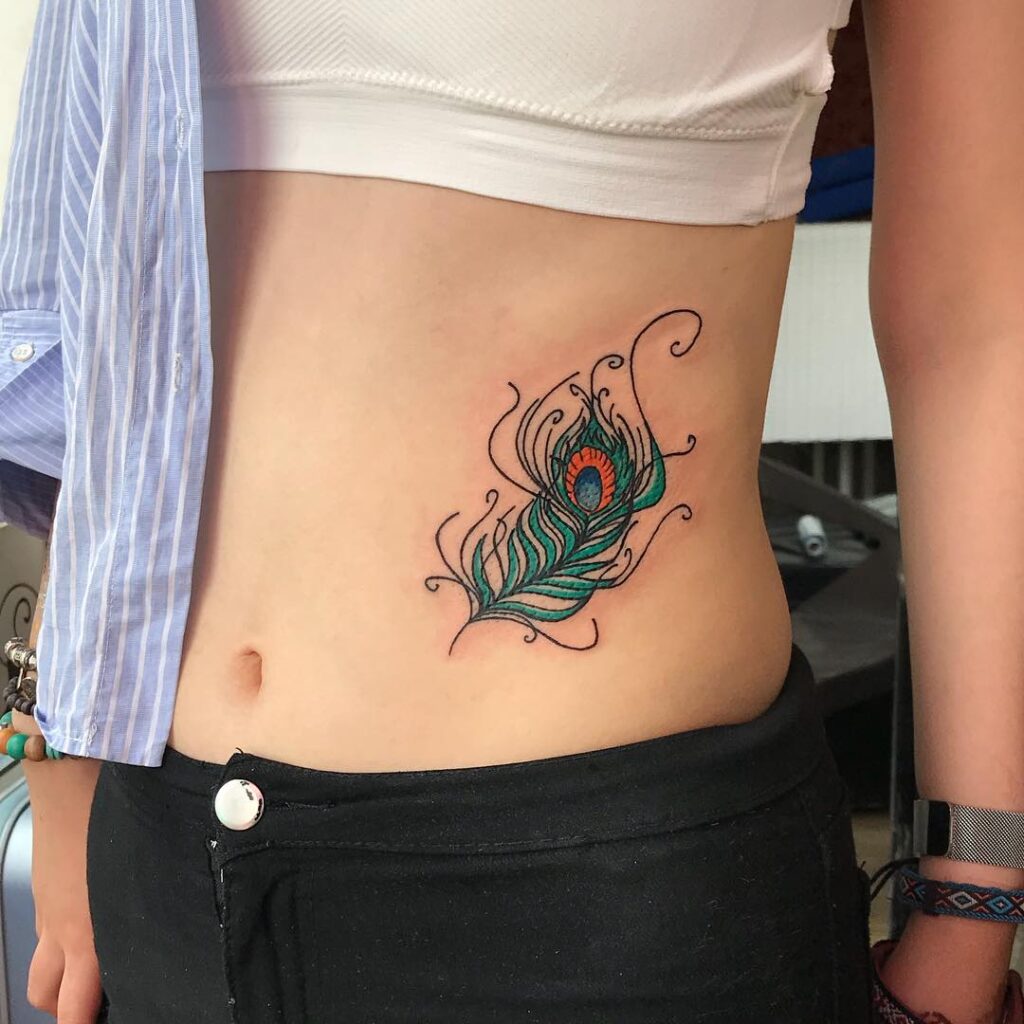 Feminine elegance peacock feather tattoo gracing the side stomach for women
