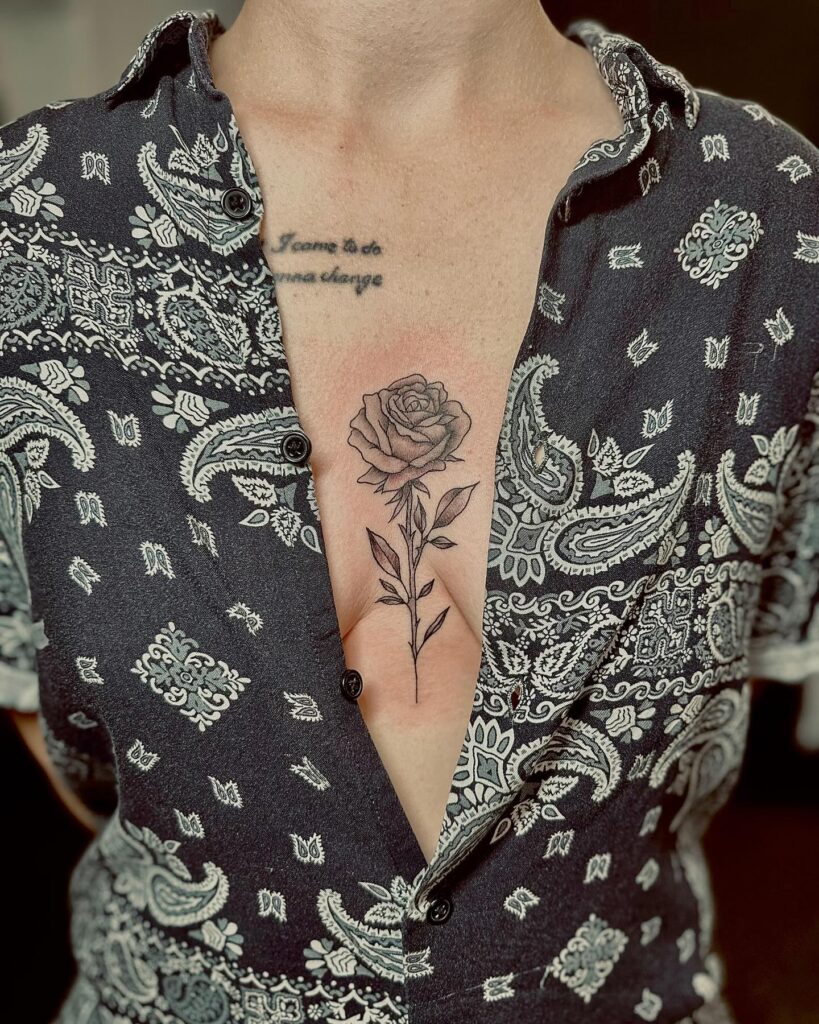 Fine-line black and gray rose sternum tattoo with delicate shading