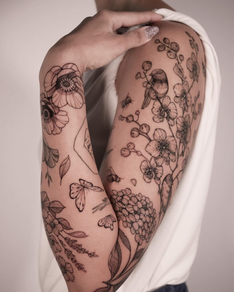 Fine-line botanical tattoo sleeve with birds, butterflies, and delicate flowers