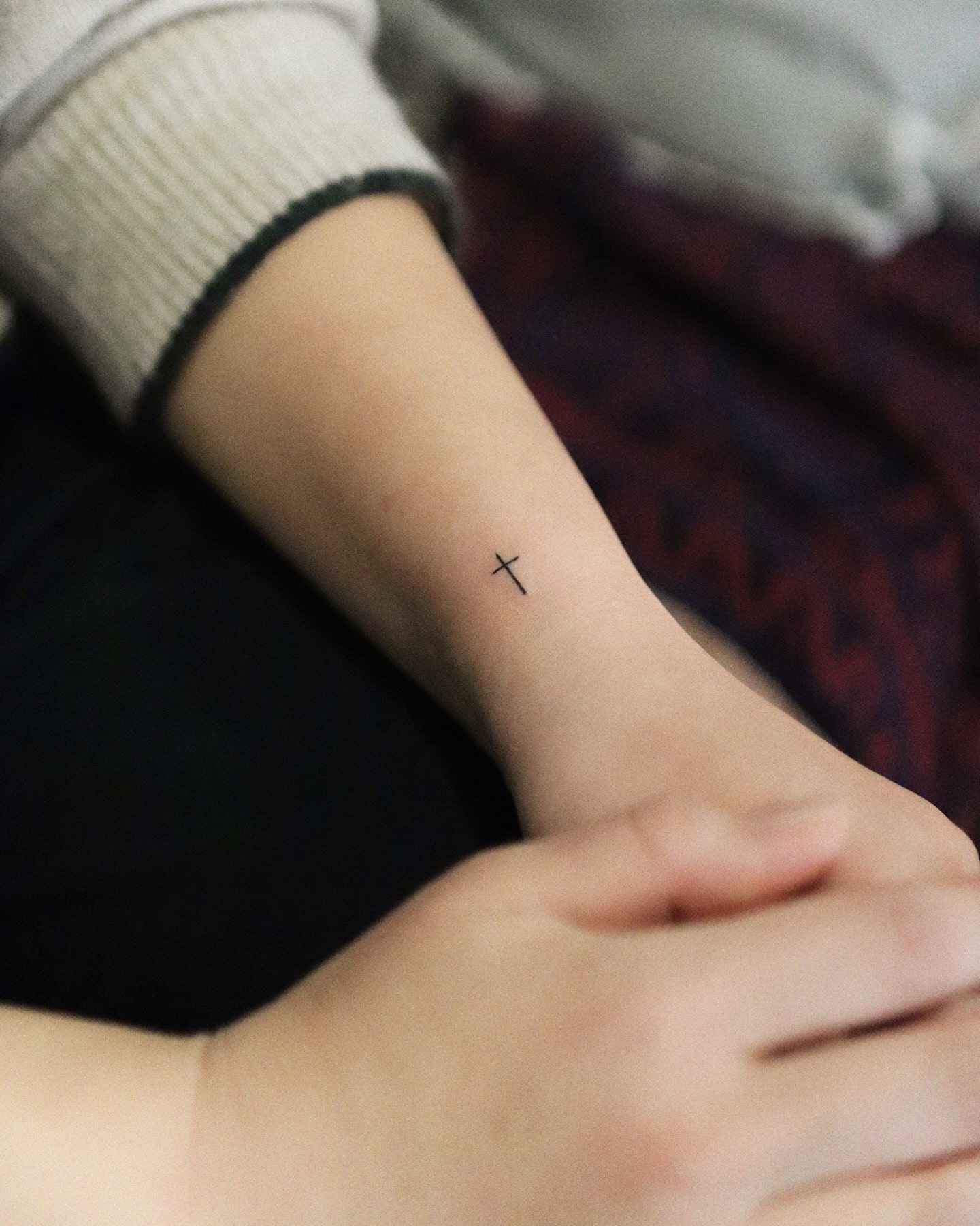 Fine line cross tattoo on wrist symbolizing faith spirituality