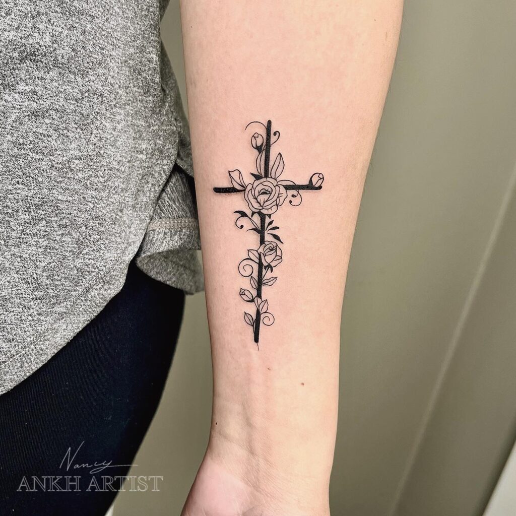 Fine line cross with roses tattoo on the forearm for girls an artistic and elegant choice