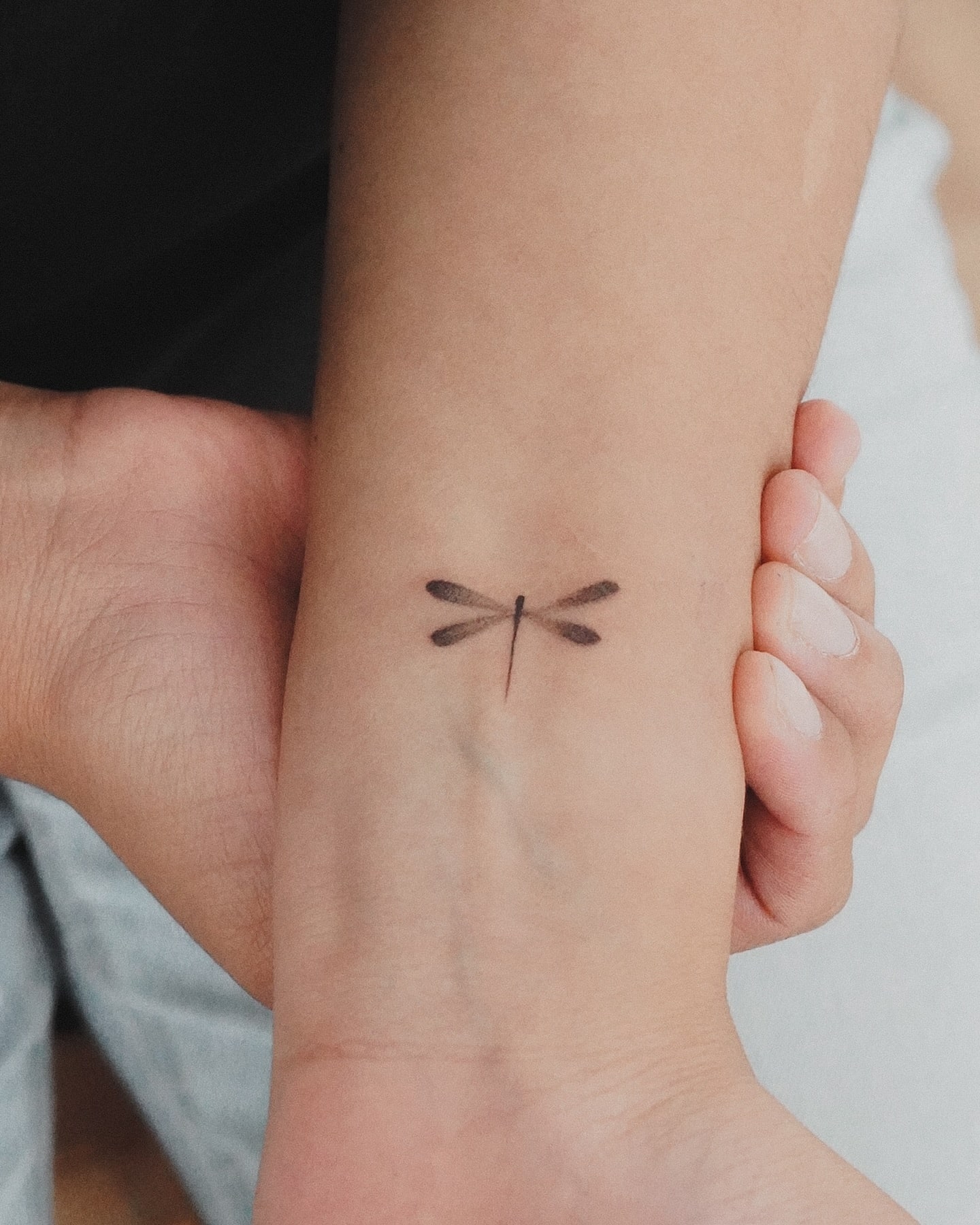 Fine-Line Dragonfly Tattoo on Wrist Symbolizing Transformation & Grace