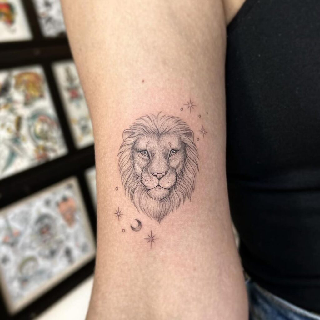 Fine line grey lion face tattoo on the bicep with stars and moon for females: celestial pride