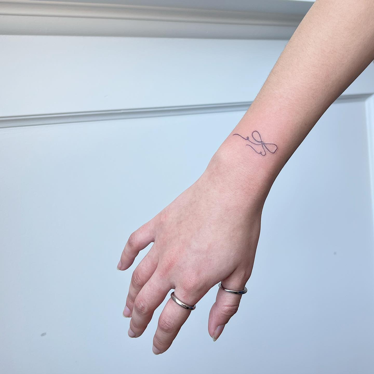 Fine-Line Minimalist Bow Tattoo on Wrist Subtle and Graceful Design