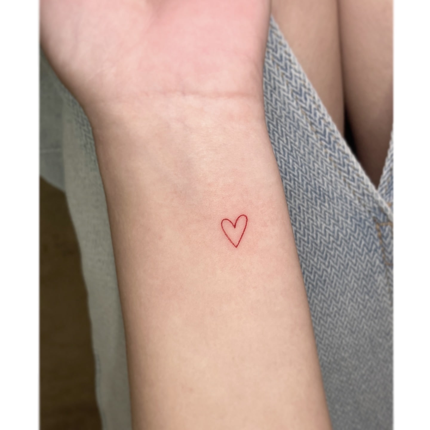 Fine-Line Red Heart Outline Tattoo on Wrist Symbolizing Love & Passion